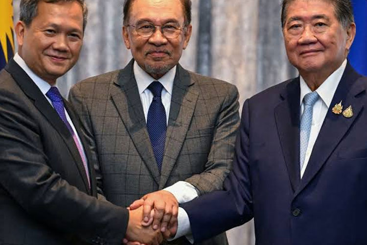 Perdana Menteri Sementara Thailand Phumtham Wechayachai (kanan) dan Perdana Menteri Kamboja Hun Manet berjabat tangan menyusul kesepakatan gencatan senjata disaksikan Perdana Menteri Malaysia Anwar Ibrahim (tengah).