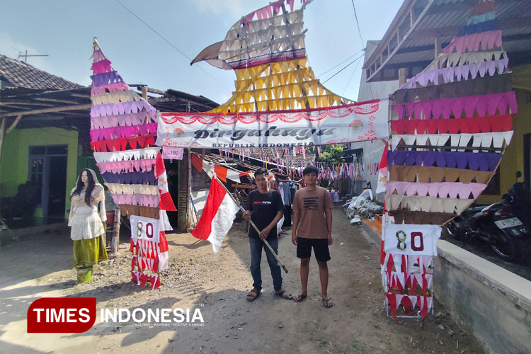 Aden (memegang bendera) pada saat menampilkan karya gapura dari limbah kain perca di Desa Sambiroto, Sooko, Kabupaten Mojokerto, Senin (11/8/2025). (Foto: Theo/TIMES Indonesia)