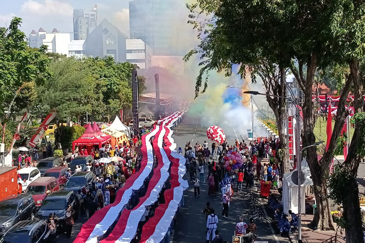 Parade pembentangan kain Merah Putih sepanjang 14 kilometer menambah semarak perayaan HUT RI di Gedung Negara Grahadi, Surabaya, Minggu (17/8/2025). (FOTO: Dok. Humas Pemprov Jatim)