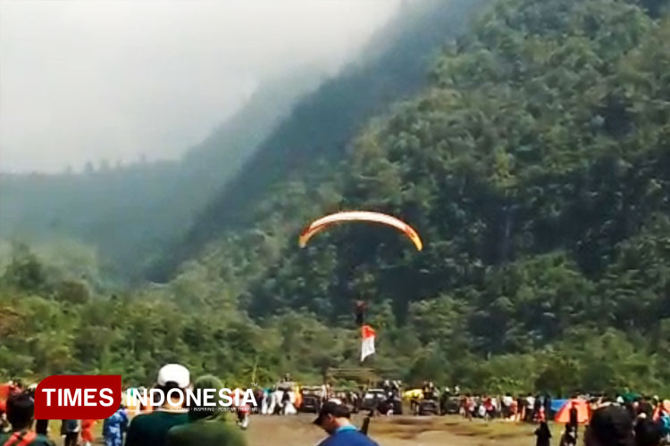 Seorang atlet paralayang saat mengibarkan Bendera Merah Putih di Kawasan Blok Pasirdatar Galunggung pada Kegiatan HUT RI ke-80 TAPA 2025. Minggu (17/8/2925) (FOTO: Harniwan Obech/TIMES Indonesia)