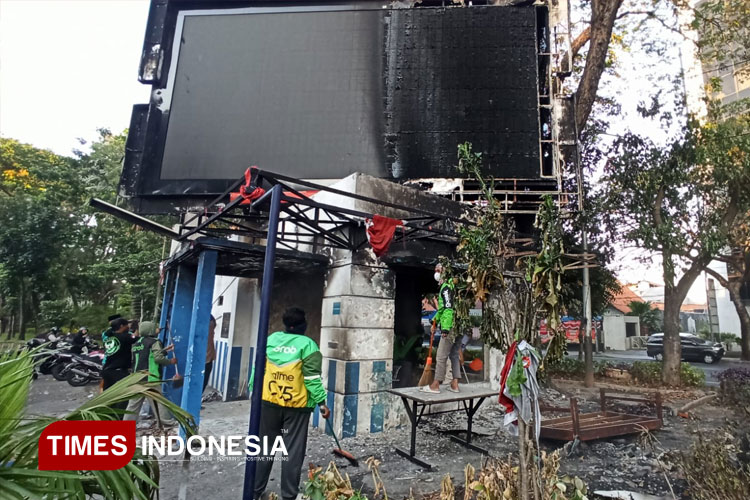Pengemudi ojek online membersihkan puing bangunan pos polisi di Surabaya, Minggu (31/8/2025).(Foto : Hamida Soetadji/TIMES Indonesia)