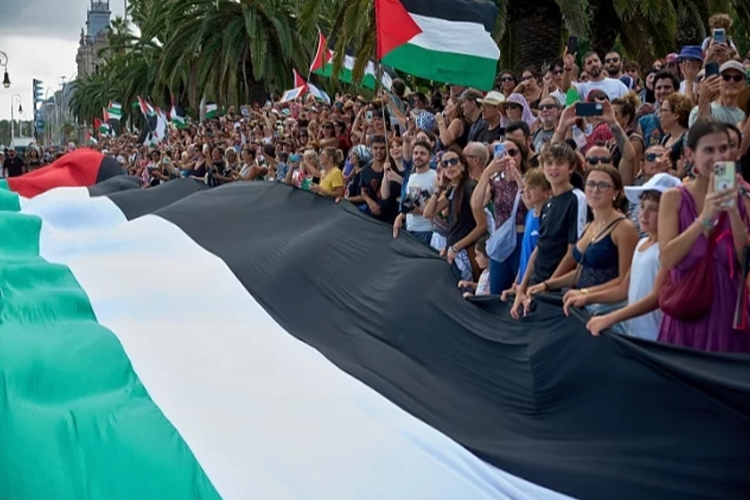 Orang-orang mengibarkan bendera Palestina saat mengucapkan selamat tinggal kepada para aktivis yang berlayar untuk bergabung dengan armada sipil menuju Gaza, di Barcelona, ​​Spanyol, pada Minggu (31/8/ 2025) (FOTO A: Euronews/AP)