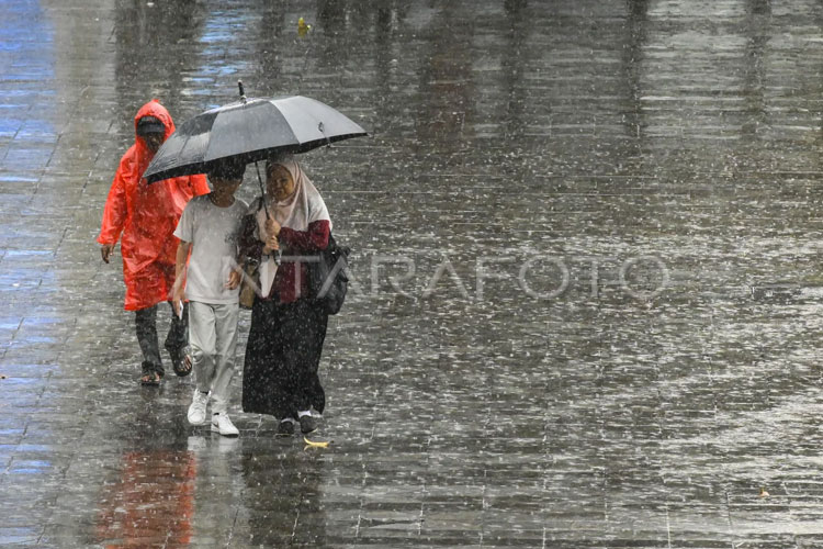 Warga menggunakan payung dan jas hujan saat hujan lebat, Sabtu (25/1/2025). BMKG memprediksi potensi cuaca ekstrem dalam empat hari ke depan di wilayah Banten, mulai 11-14 September. (ANTARA FOTO/Sulthony Hasanuddin)