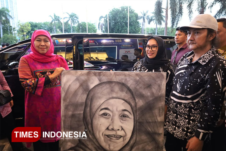 Gubernur Jawa Timur Khofifah Indar Parawansa saat berpose dengan lukisan dirinya yang dibuat eks ODGJ asal Bondowoso (FOTO: Muzayyanah for TIMES Indonesia)