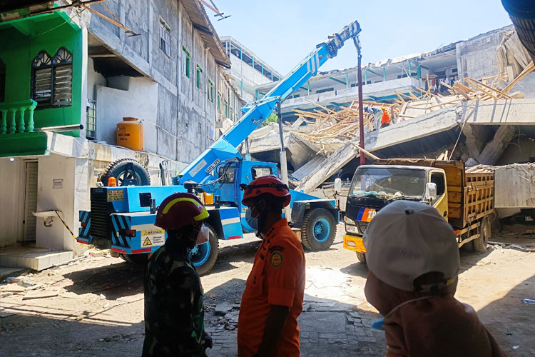 Tim SAR gabungan saat proses evakuasi material bangunan menggunakan alat berat.