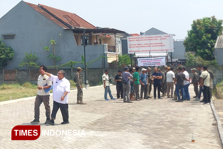 Kepala Dinas Perkim CKTR Sidoarjo M Bachruni Aryawan (depan kanan) saat akan membongkar pembatas jalan Mutiara City namun ditolak warga Mutiara Regency. (FOTO: Syaiful Bahri/TIMES Indonesia)