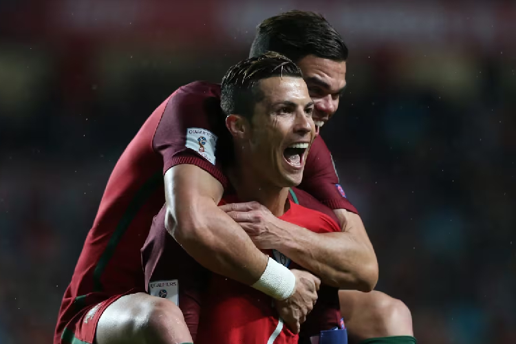 Striker Portugal Cristiano Ronaldo mengendong Pepe usai mencetak gol ke gawang Hungaria di kualifikasi Piala Dunia 2026. Gol ini membawa Ronaldo sebagai pencetak gol terbanyak di kualifikasi Piala Dunia. (foto: FIFA)
