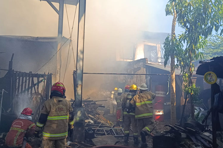 Petugas damkar berusaha memadamkan api yang menjalar disekitar bengkel dan mess sopir di Jalan Tembok Gede III Surabaya, Kamis (16/10/2025). (Foto: Dok.Dinas PMK Surabaya)