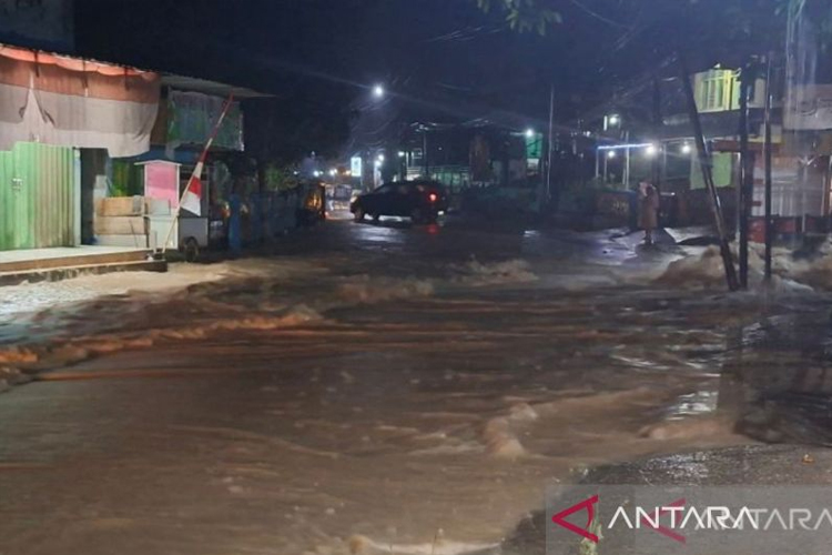 Warga melintas di jalan yang tergenang banjir di Kelurahan Potu, Kabupaten Dompu, Nusa Tenggara Barat, Minggu (9/11/2025).