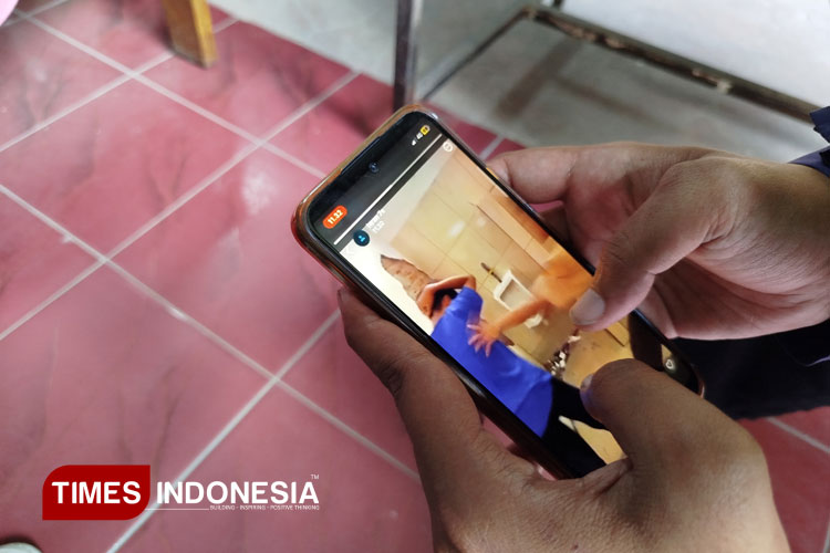 Salah satu warga sedang menonton video yang beredar tentang perundungan siswa SMP di Blora. (FOTO: Rengga/TIMES Indonesia)