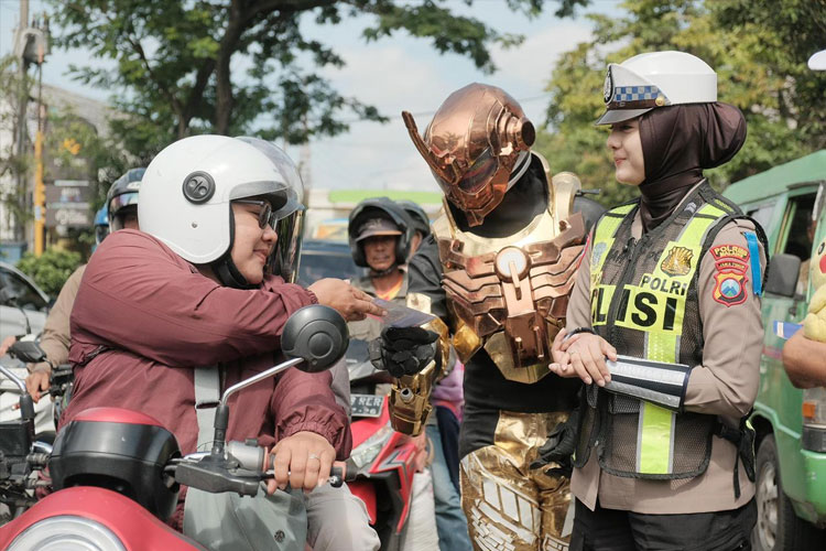 Polisi Super Hero Tegur Pengendara di Simpang Jalan